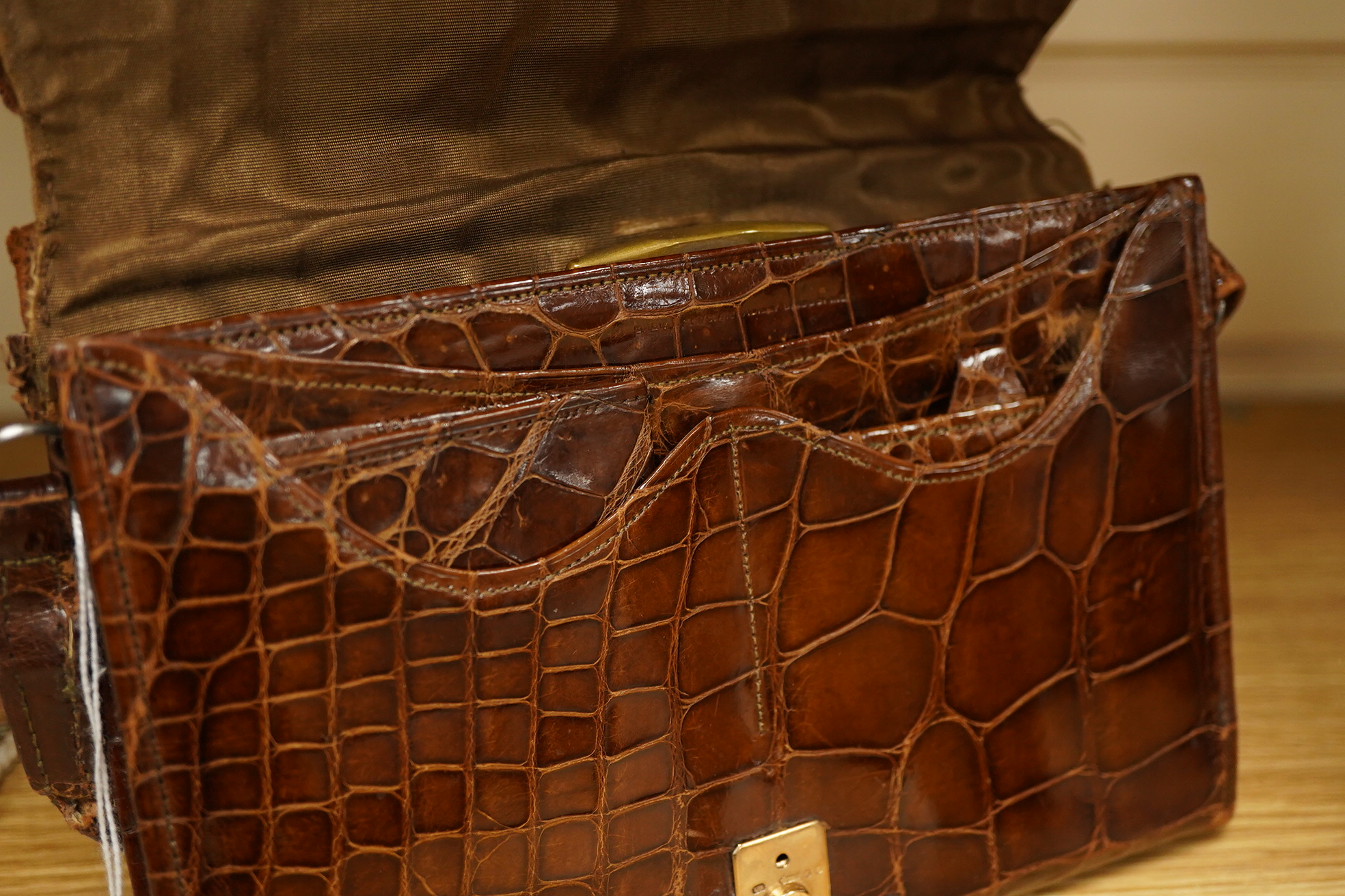 A stylish 1930's ladies 9ct gold mounted brown crocodile handbag, fitted with small wallet and mirror, 21.5cm wide x 15cm high. Condition - the corners to base, top and handle have wear, the silk lining has a small split